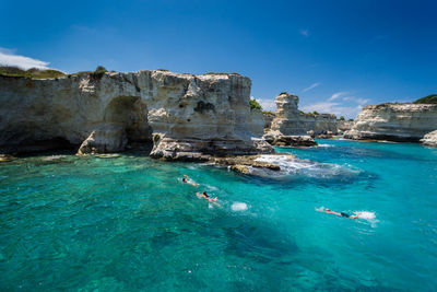 Rocks in sea against blue sky