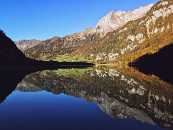 Scenic view of lake and mountains against clear blue sky