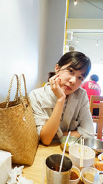 Young woman looking away while sitting on table