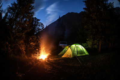 Illuminated tent on field against sky at night