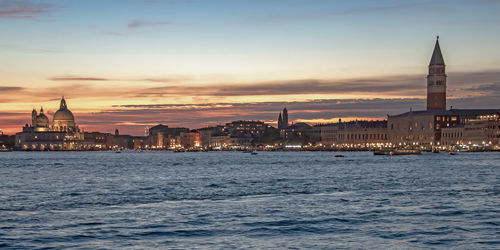 City at waterfront against sky during sunset