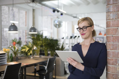 Portrait of a businesswoman in office, using digital tablet