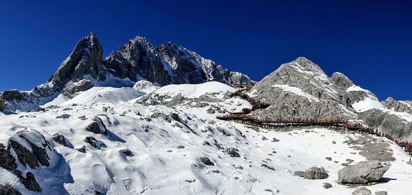 Scenic view of snowcapped mountains against clear blue sky