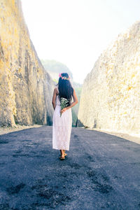 Rear view of woman standing on road against clear sky