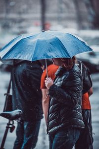 Rear view of people walking on road during rainy season