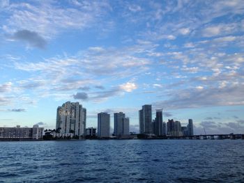 Sea by buildings in city against sky