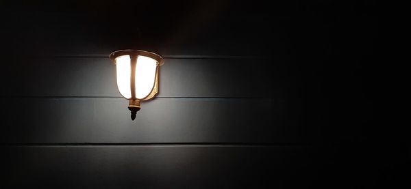 Low angle view of illuminated light bulb in darkroom