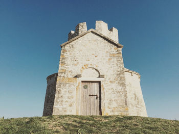 Low angle view of historic church on field against sky