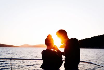 Silhouette of people standing on mountain at sunset