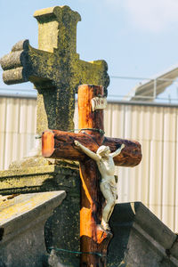 Close-up of cross on stone against sky