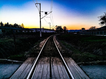 Railway tracks against clear sky at sunset