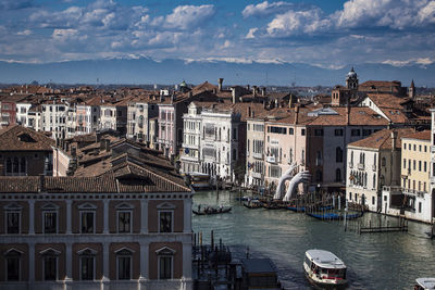 River amidst buildings in city against cloudy sky