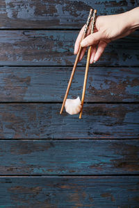 Cropped hand holding dumpling with chopsticks