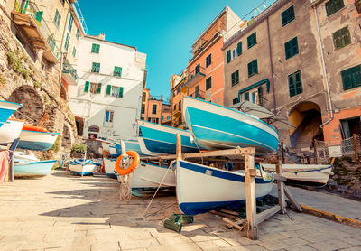 Boats moored by buildings in city against clear sky