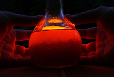 Cropped hands holding drink in glass bottle on table