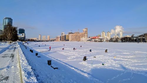 Snow covered buildings in city against sky