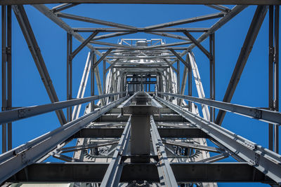 Low angle view of electricity pylon against clear blue sky