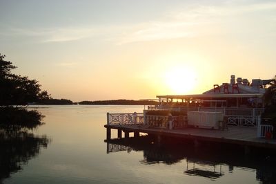 Bar by lake against sky during sunset