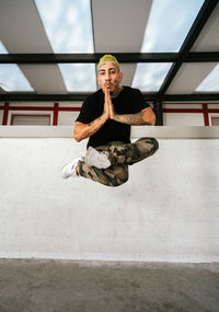 Full body of young tattooed man performing break dance movement and leaping over ground