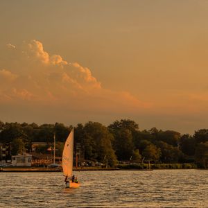 Sailboat sailing on lake against sky during sunset