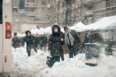 People standing on snow covered street in city