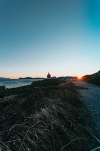 Man sitting on land against sky during sunset