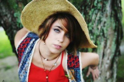 Portrait of beautiful woman wearing hat against tree