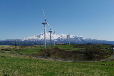 Wind turbines on field against sky