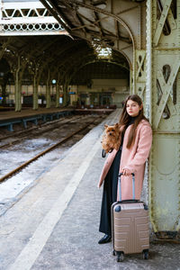 Young girl in pink coat at train station. beautiful woman stands on platform