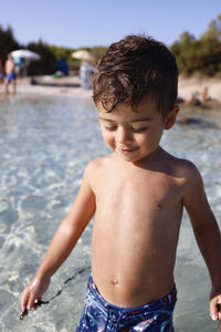 Portrait of shirtless boy standing at beach