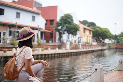 Rear view of woman with umbrella against canal