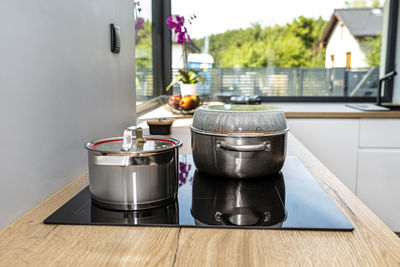 Steel pots with a cooking dish on an induction cooker built into the kitchen worktop on the cabinets