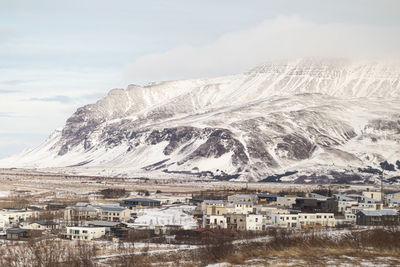 Aerial view of townscape by snowcapped mountain against sky