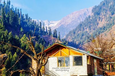 House by trees and mountains against sky