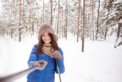 Portrait of smiling woman standing on snow covered land