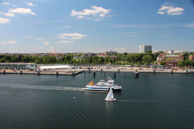 Nautical vessel on river by buildings in city against sky