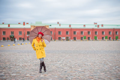 Full length of woman standing on umbrella against rain