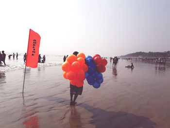 Red balloons on beach against clear sky