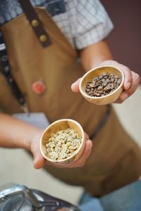 Midsection of man holding coffee beans in bowls