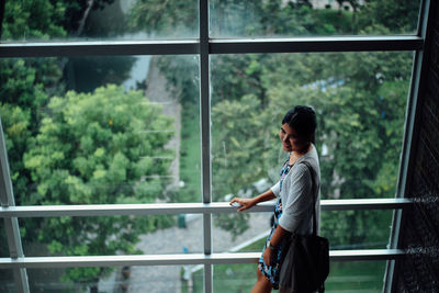 Smiling woman standing against window