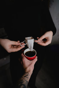 Holding coffee mug over paper filter, coffee brewing concept