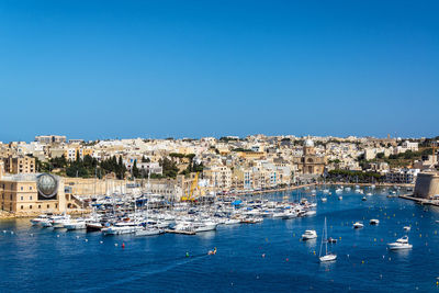 Sailboats in sea against buildings in city