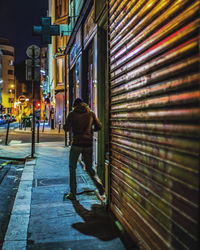 Rear view of woman walking on street at night