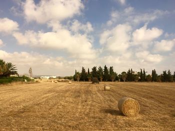 Hay bales on field against sky