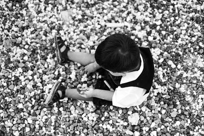 High angle view of girl sitting on pebbles