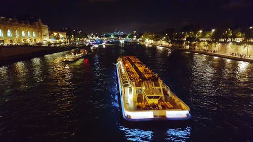 Sailboats in city by sea against sky at night