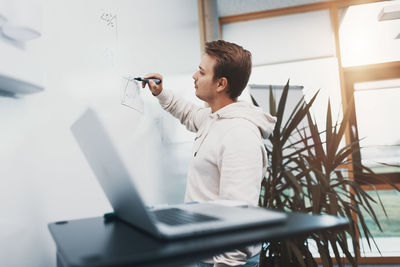 Young business man writes on a whiteboard, he is busy and works hard in his start up company