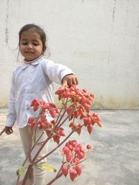 Cute girl holding flowers against wall