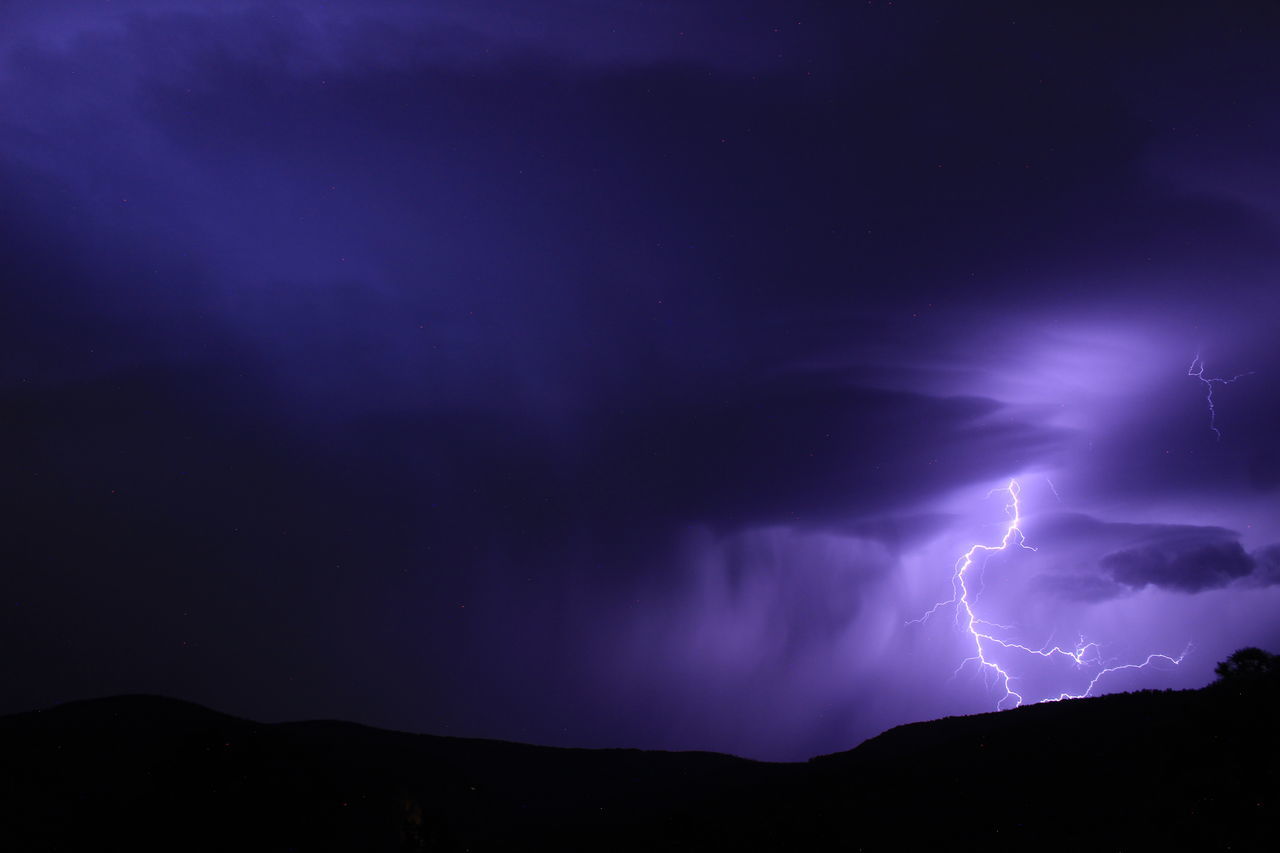 lightning, power in nature, thunderstorm, storm, cloud, beauty in nature, night, thunder, sky, dramatic sky, warning sign, environment, storm cloud, sign, communication, purple, nature, mountain, forked lightning, scenics - nature, no people, outdoors, dark, awe, silhouette, electricity, landscape, atmospheric mood, light - natural phenomenon, extreme weather, darkness, illuminated