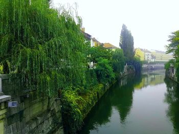 Scenic view of river by trees and building against sky